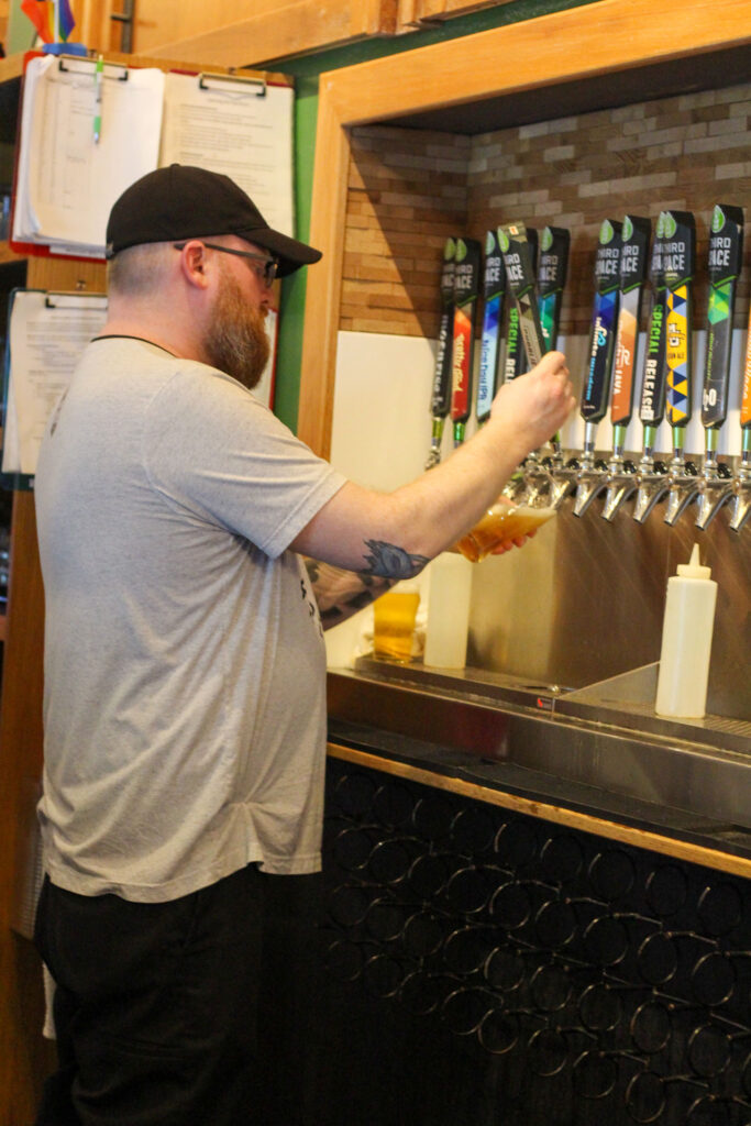 Third Space Brewing staff member pouring beer from a row of taps during the CVI event.