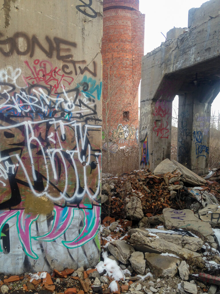 Graffiti-covered brick interior with collapsed debris inside the former Coca-Cola bottling plant near Bay View