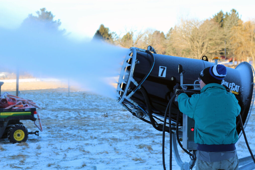 A volunteer operates a snowmaking machine producing artificial snow at Lapham Peak.