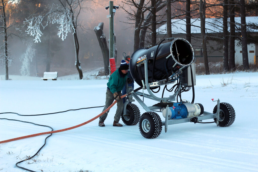 A volunteer operates a snowmaking machine on a snowy trail at Lapham Peak.