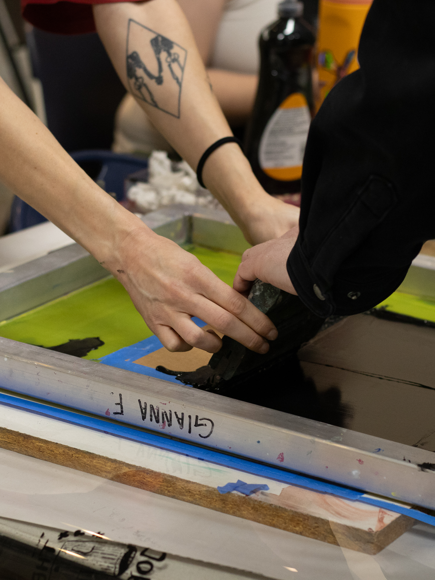 Hands pulling ink across a screen printing frame at Milwaukee Zine Fest