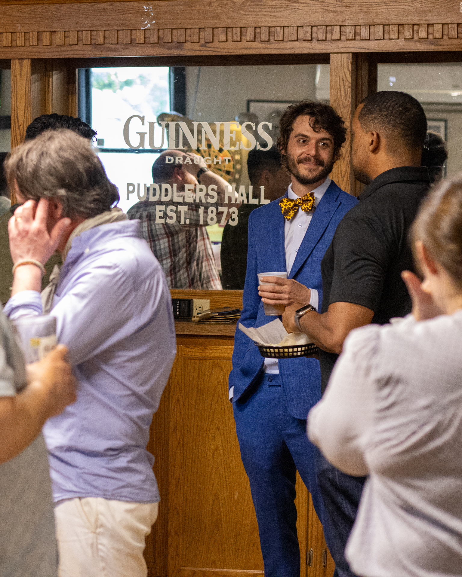 A guest in a blue suit at the bar at Puddler's Hall in Bay View, Milwaukee, with the Puddlers Hall mirror behind him during the PINTS event